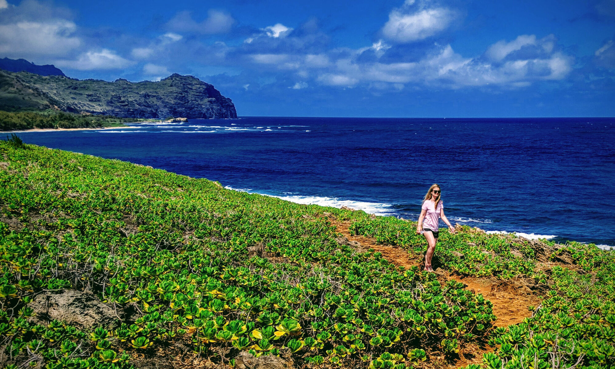 Woman hiking Maha'ulepu Heritage Trail along the ocean shore of Kauai, Hawaii.