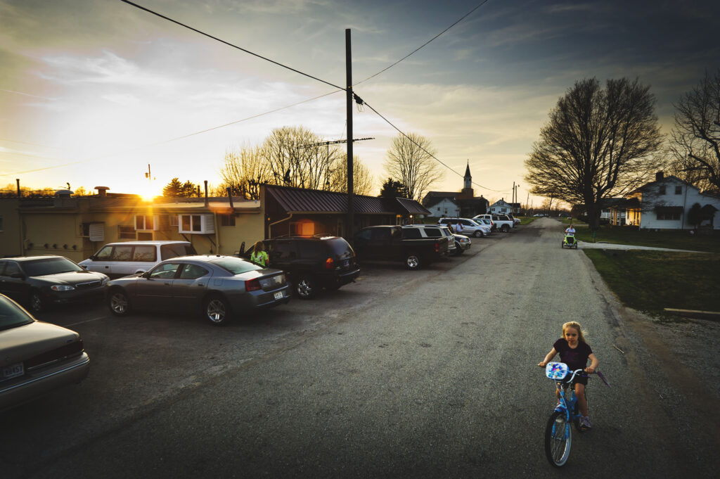 A small girl rides a bike on Enochsburg Road outside the Fireside Inn.