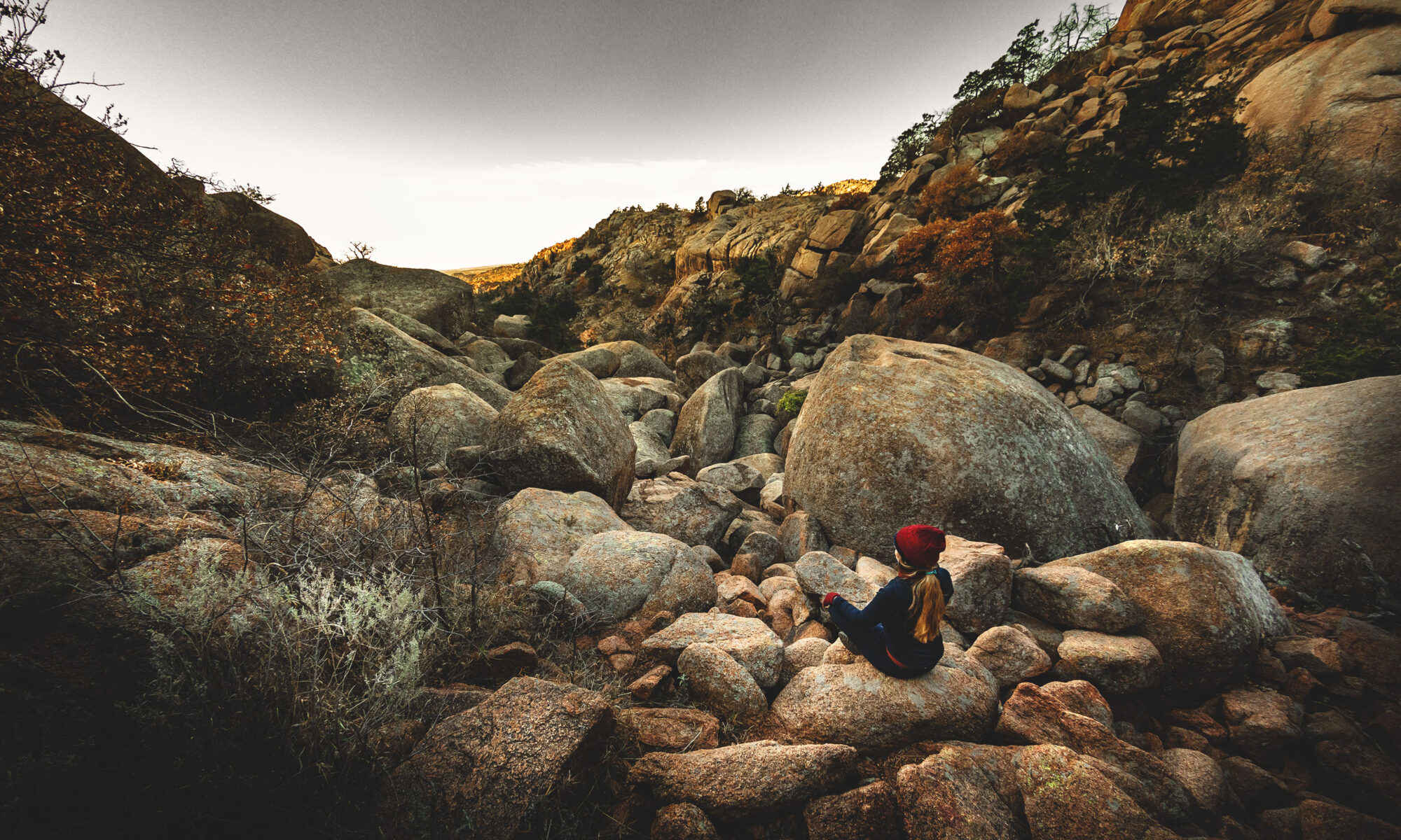 Woman sitting cross-legged overlooking the Valley of Boulders in the Wichita Mountains Wildlife Refuge.