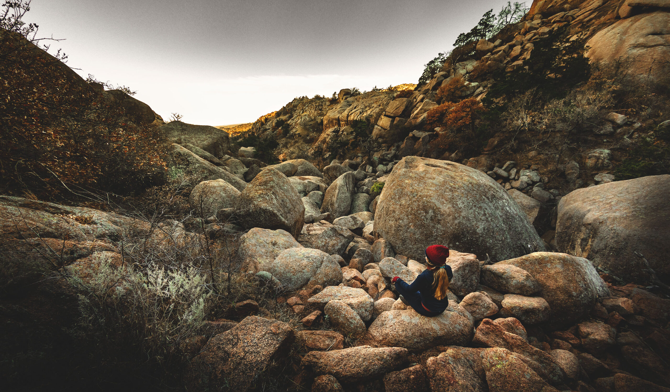 Woman sitting cross-legged overlooking the Valley of Boulders in the Wichita Mountains Wildlife Refuge.