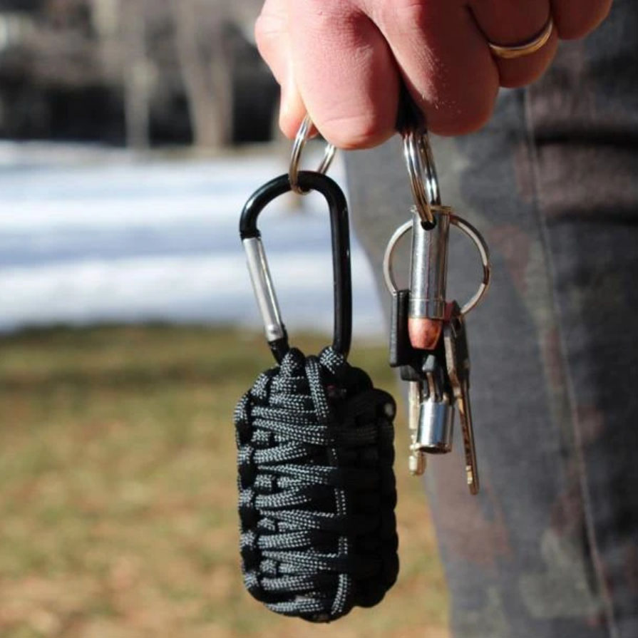 Hand holding Paracord Grenade Survival Kit on keychain.