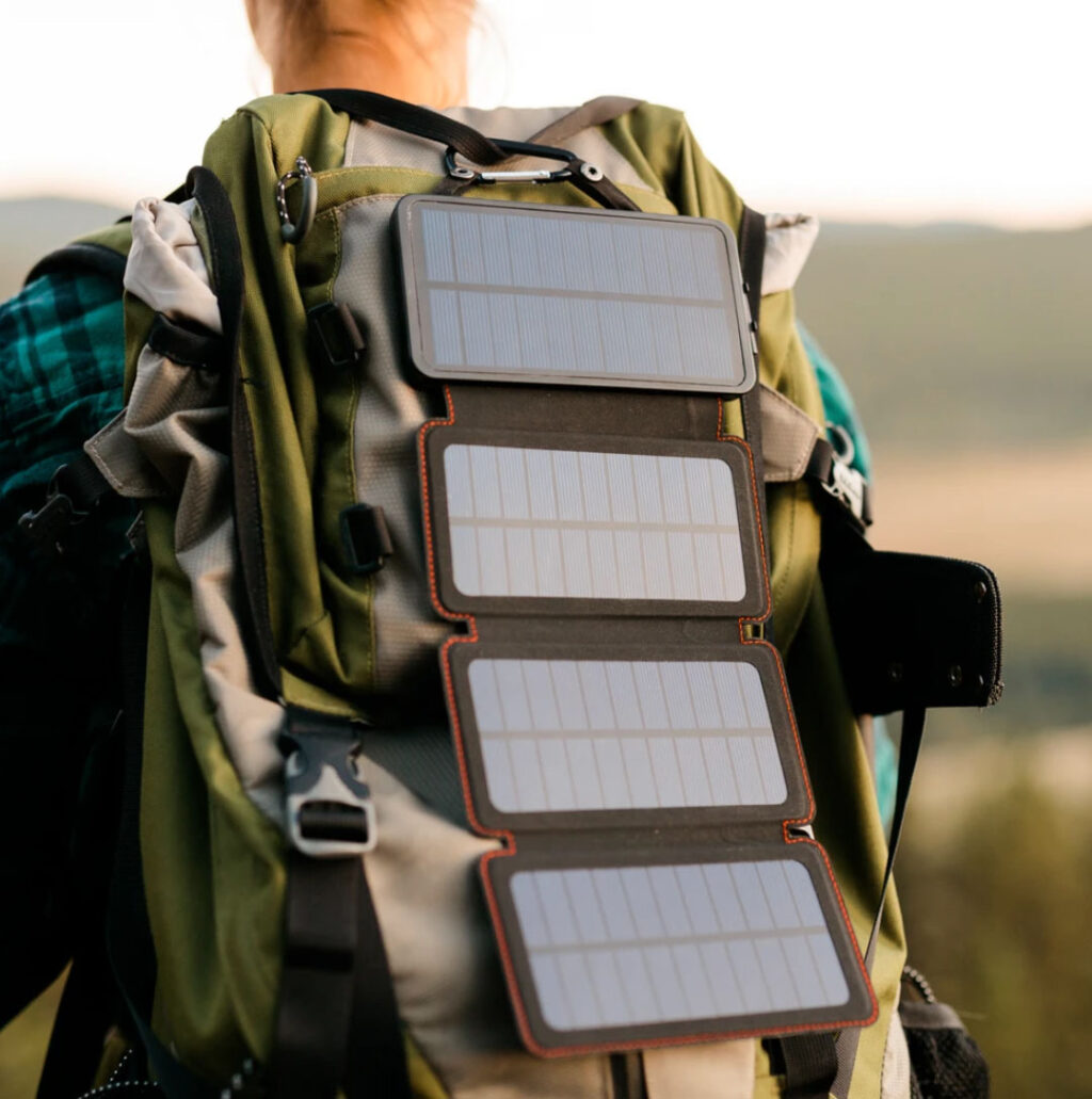 Hiker with SOLAR WIRELESS PHONE CHARGER attached to backpack.