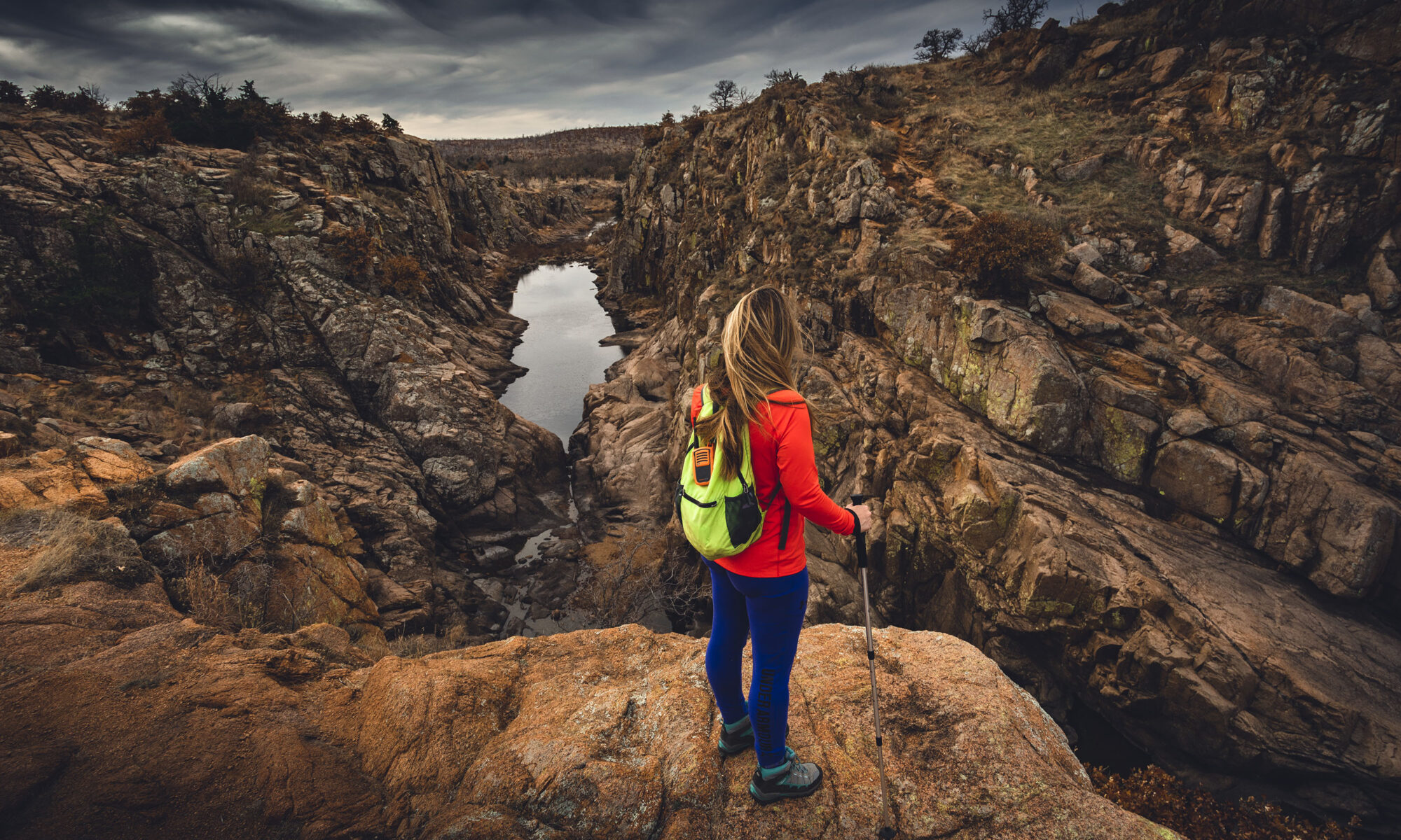 Woman hiker on cliff edge overlooking Forty Foot Hole from Kite Trail Wichita Mountains Wildlife Refuge.