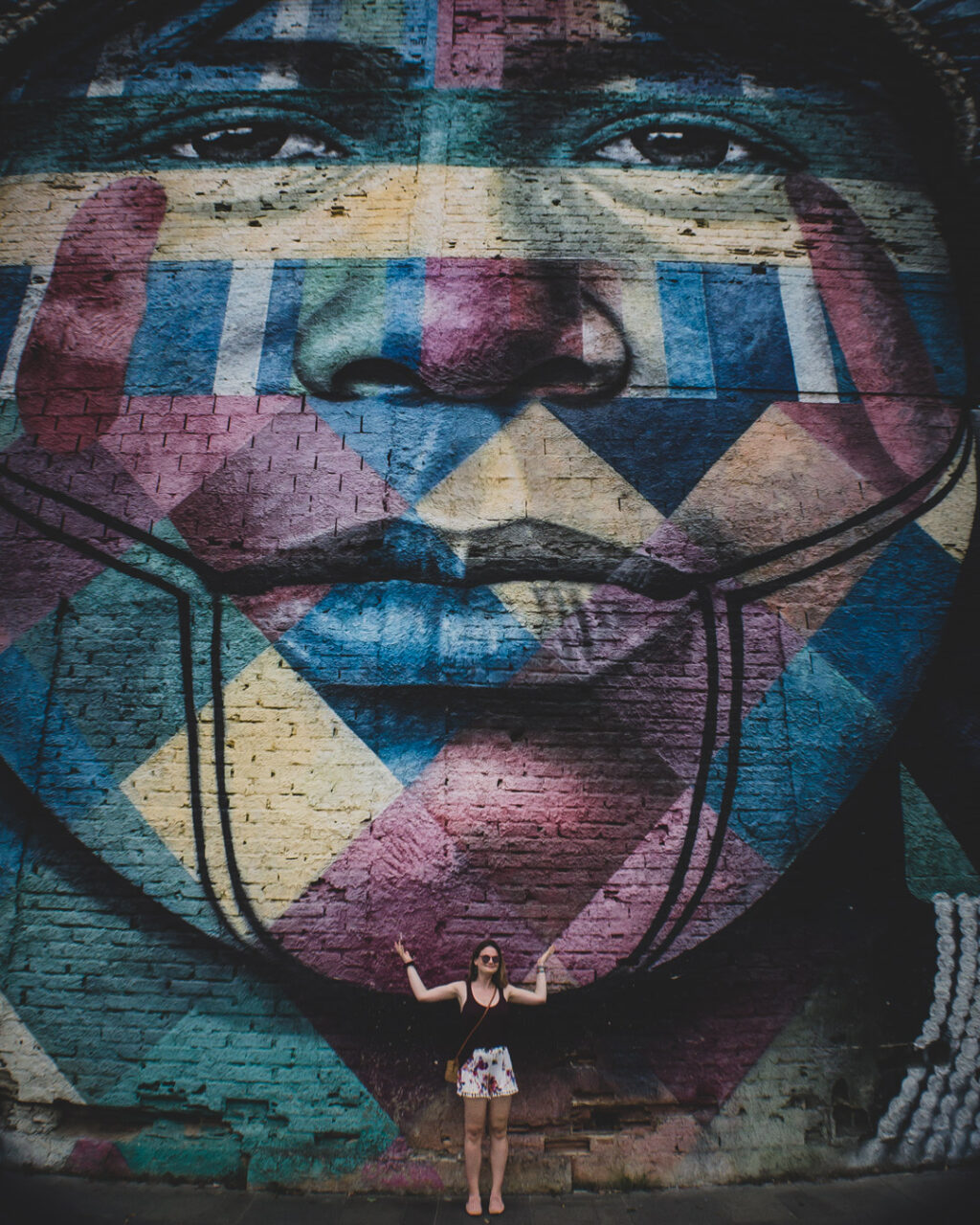 Woman posing for a photo in front of Ethnic Groups mural by Eduardo Kobra in Rio de Janeiro, Brazil.
