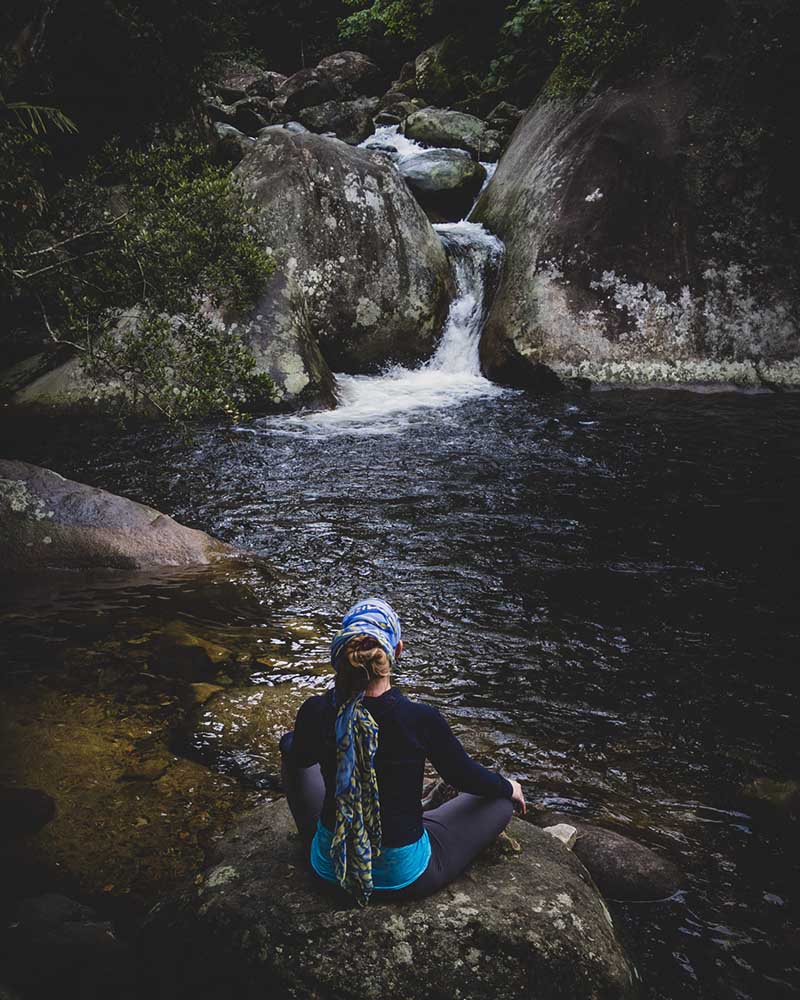Woman meditating on rock at Poço Dois Irmãos (Two Brothers Well) in Serra dos Órgãos National Park.