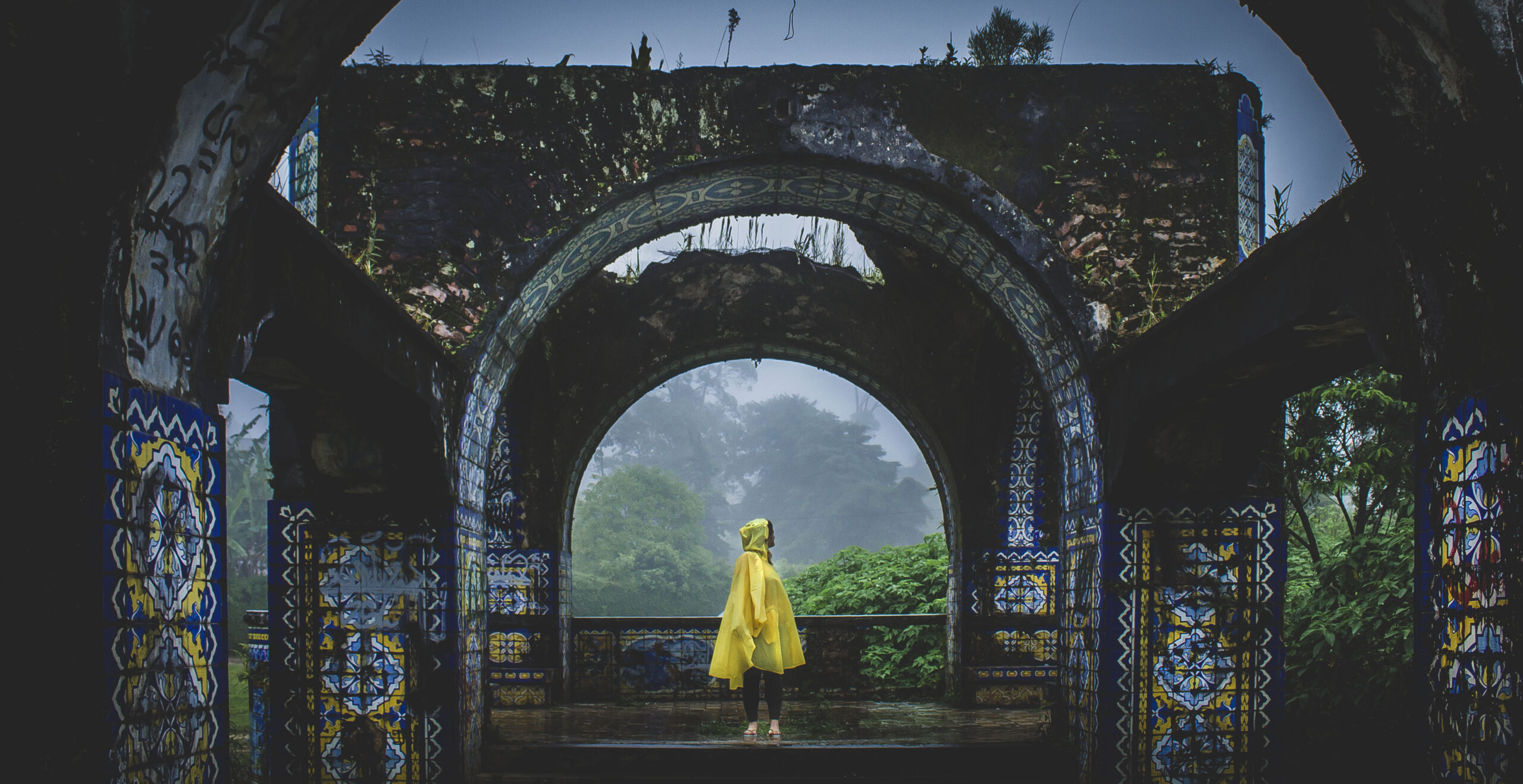 Woman in yellow poncho standing in abandoned Mirante da Granja Guarani in Teresopolis, Brazil.
