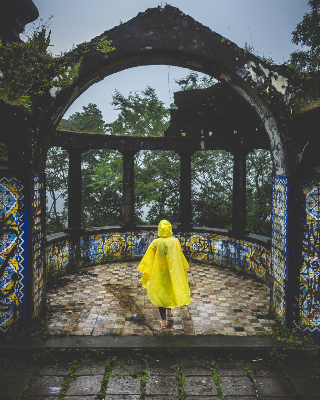 Woman in yellow poncho walking among the ruins of Mirante da Granja Guarani in Teresopolis, Brazil.