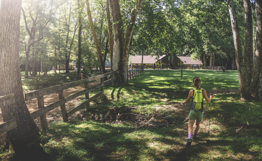 A woman hikes toward the saddle barn along a wooden fence at Brown County State Park in Indiana.